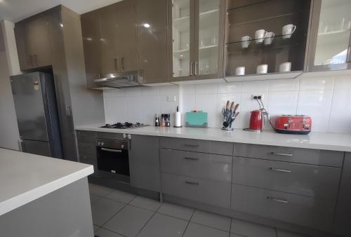 uma cozinha com armários cinzentos e um frigorífico em Resort style 1 or 2 bedroom with pool and free parking em Hornsby