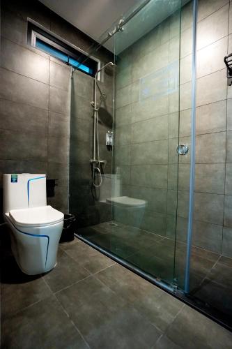 a bathroom with a toilet and a glass shower at Heddin Homestay in Ben Tre