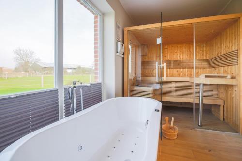 a bath tub in a room with a large window at Büdlfarm - Der Familien-Erlebnishof in Strandnähe in Fehmarn