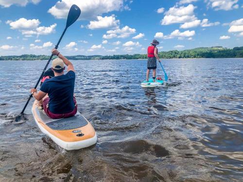 two men are on paddle boards on a lake at LACS in Saulieu