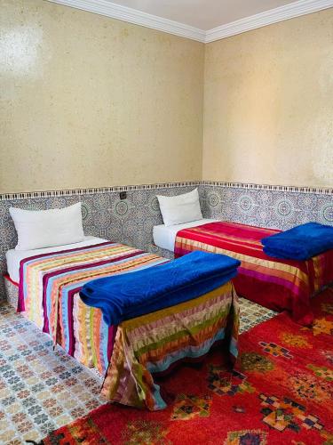 two beds in a room with blue and red at Bivouac Lot Of Stars in Ouarzazate