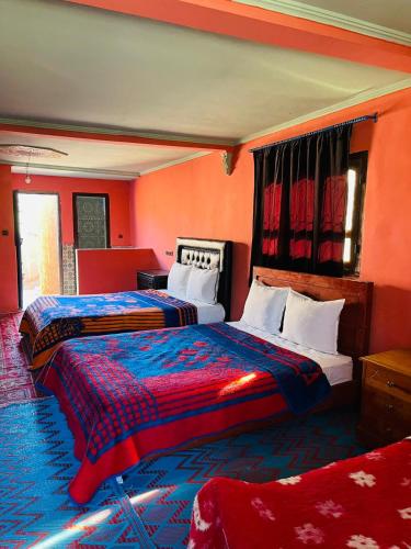 two beds in a room with orange walls at Bivouac Lot Of Stars in Ouarzazate