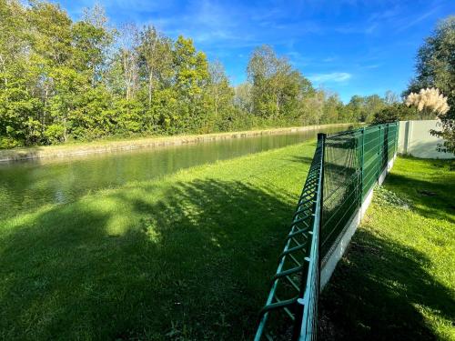 a fence next to a body of water at Gîte du canal rue de la Tuilerie in Amilly