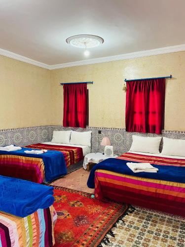 a room with three beds and red curtains at Bivouac Lot Of Stars in Ouarzazate