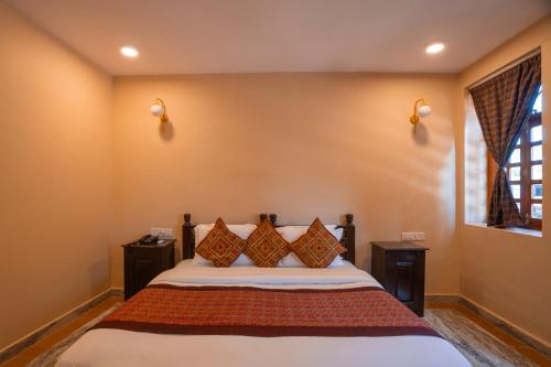 a bedroom with a bed with two night stands and a window at Hotel Helsinki House in Jaisalmer