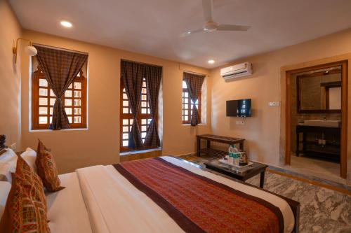 a bedroom with a bed and a television and windows at Hotel Helsinki House in Jaisalmer
