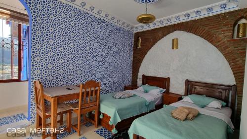 a room with two beds and a table with a desk at Casa Meftah Blue in Chefchaouene