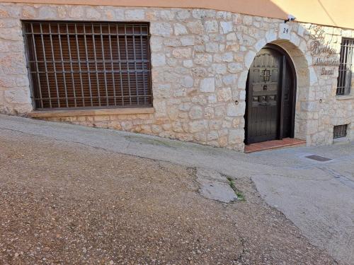 un edificio de piedra con puerta y ventana en Casa Rural LA BODEGA, ofrece cata de vino gratis en Horche