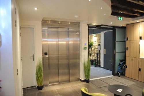 an office lobby with a glass door with two plants at Hôtel De La Herse d'Or in Paris