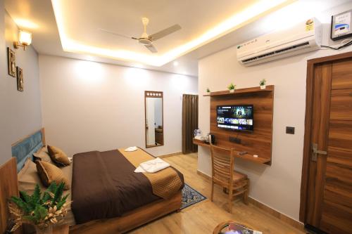 a bedroom with a bed and a desk and a tv at Hotel Mahadev Rishikesh in Rishīkesh