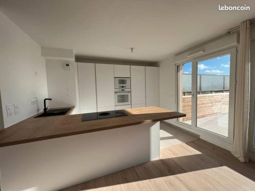 une cuisine avec des placards blancs et un comptoir en bois dans l'établissement Appartement duplex dernier étage - vue panoramique, à Bagneux