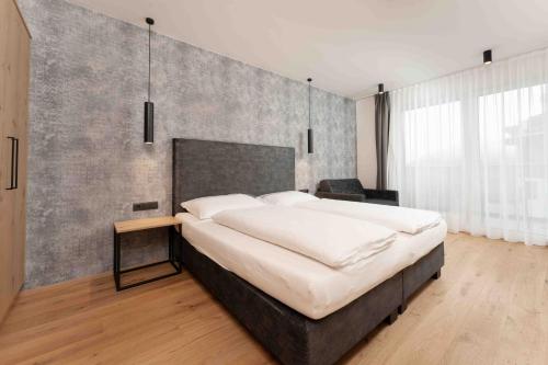 Un dormitorio con una cama grande con una pared de hormigón. en A CASA Serenity, en Serfaus