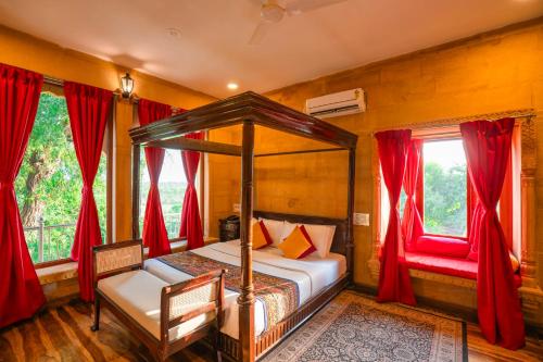 a bedroom with a canopy bed and red curtains at Hotel Helsinki House in Jaisalmer