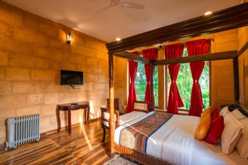 a bedroom with a four poster bed with red curtains at Hotel Helsinki House in Jaisalmer