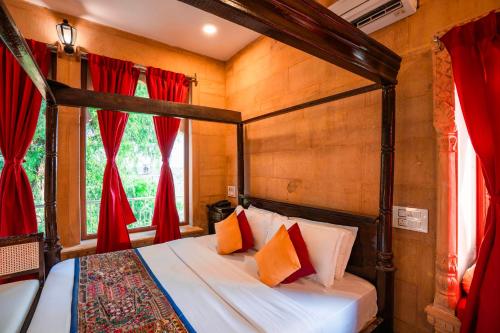 a bedroom with a four poster bed with red curtains at Hotel Helsinki House in Jaisalmer