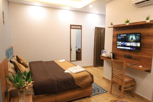 a bedroom with a bed and a desk and a television at Hotel Mahadev Rishikesh in Rishīkesh