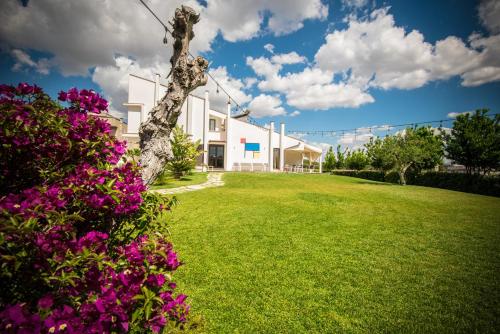 a house with a green yard with flowers at Locanda del Pino in Ginosa Marina