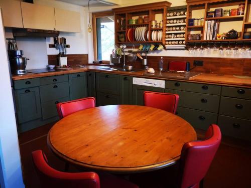 una cucina con tavolo in legno e sedie rosse di Un superbe chalet tout proche de Mens a Mens