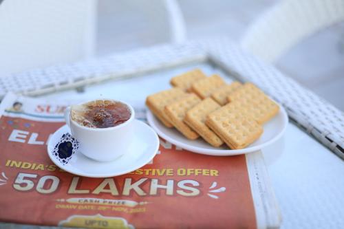 a cup of coffee and biscuits on a magazine at Hotel Mahadev Rishikesh in Rishīkesh