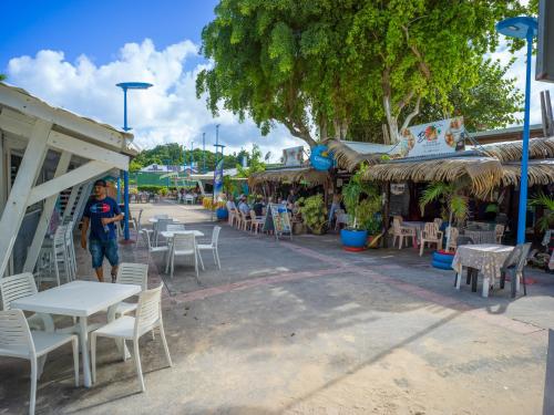 a man standing in front of a restaurant with tables and chairs at RDC appartement en bord de mer au son des vagues in Le Moule