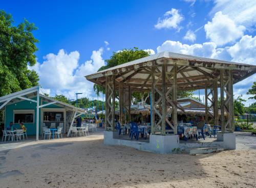 a pavilion with tables and chairs on the beach at RDC appartement en bord de mer au son des vagues in Le Moule