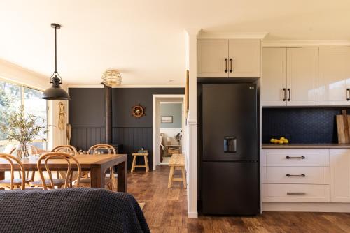 eine Küche und ein Esszimmer mit einem schwarzen Kühlschrank in der Unterkunft Lobster Pot Cabin in Coles Bay