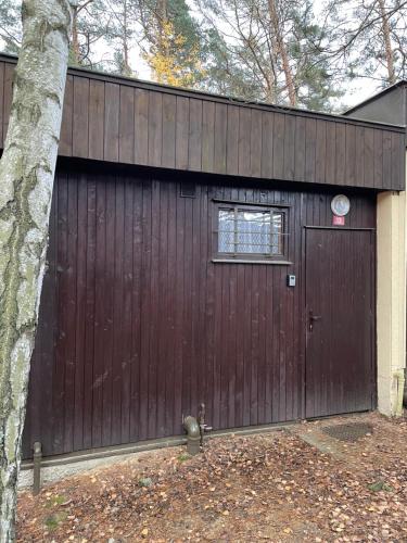 a garage with a brown door and a tree at Chata Svoboda in Doksy