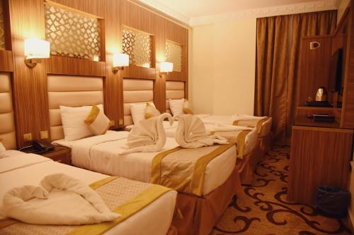 a hotel room with four beds with towels on them at Al Andalus Palace 1 Hotel in Al Madinah