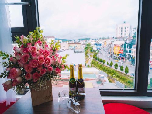 una mesa con dos botellas de vino y un ramo de rosas en Le Tuan Minh Hotel, en Da Lat