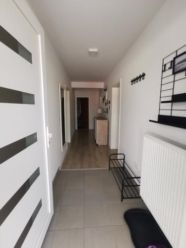un pasillo con paredes blancas y una habitación con mesa en Apartment Mejdan, en Tuzla