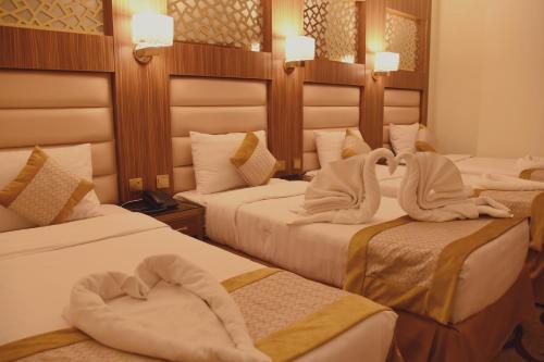a hotel room with three beds with towels on them at Al Andalus Palace 1 Hotel in Al Madinah