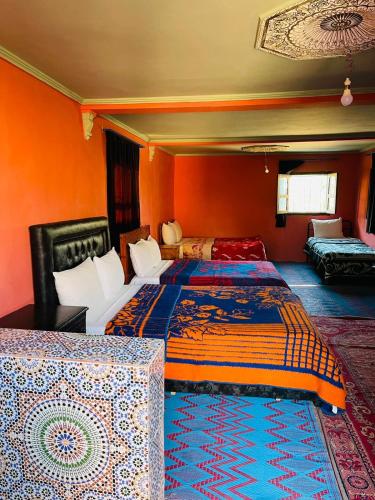 two beds in a room with orange walls at Bivouac Lot Of Stars in Ouarzazate