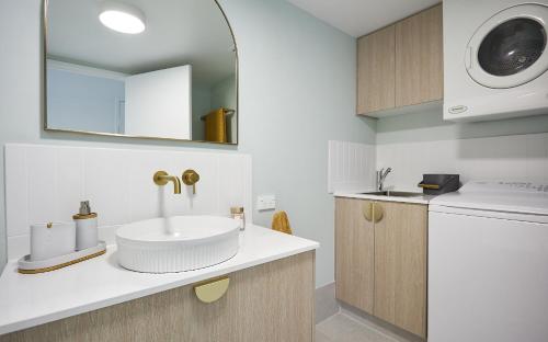 a bathroom with a sink and a washing machine at Main Beach Coastal Apartment in Gold Coast
