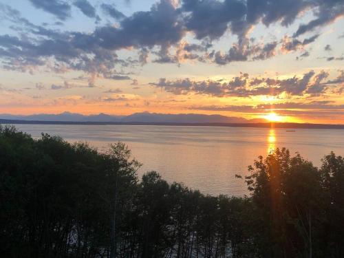 a sunset over a large body of water at 1-Bedroom Seaview Guesthouse on Seattle Luxury Estate with Views of Olympic Mountains in Seattle