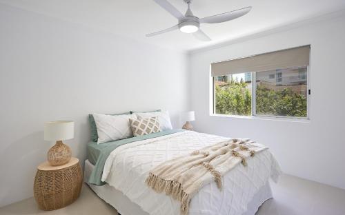 a white bedroom with a bed and a window at Main Beach Coastal Apartment in Gold Coast