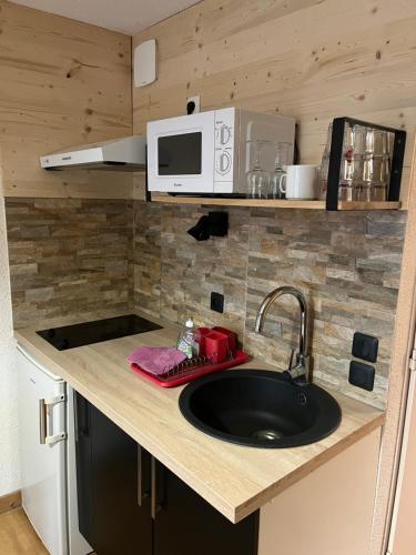 a kitchen counter with a sink and a microwave at Appartement Tout Confort in Morillon