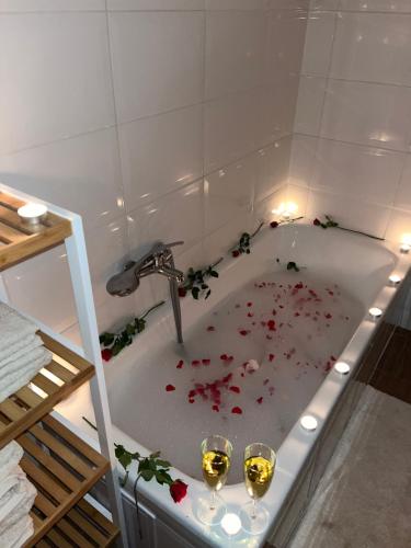 una vasca da bagno con due bicchieri di vino e fiori di Kerekerdő Apartman - Szarvaskő a Szarvaskő