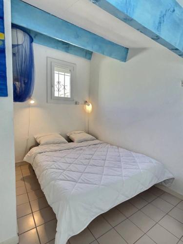 - une chambre blanche avec un lit et un plafond bleu dans l'établissement Goy, à Valras-Plage
