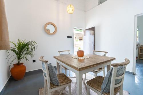 a dining room with a wooden table and chairs at Coconut Cottage - Hiriketiya Beach in Hiriketiya