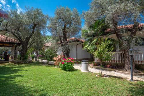 a yard of a house with trees and flowers at President Bungalows and Apartments in Utjeha