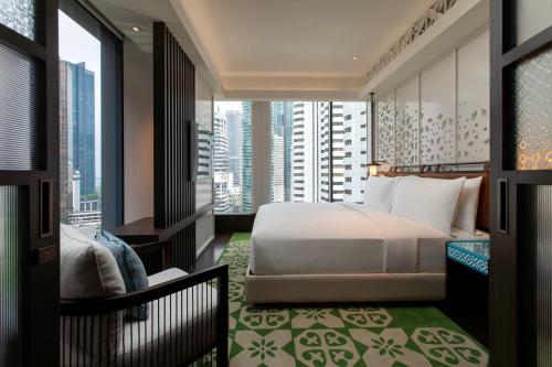a bedroom with a bed and a view of a city at Hotel Indigo Kuala Lumpur on the Park by IHG in Kuala Lumpur