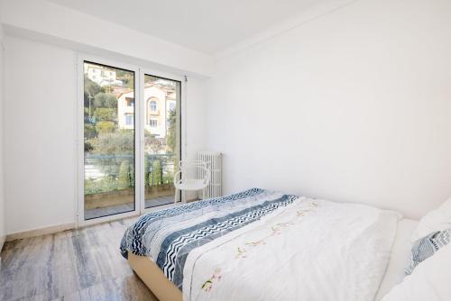a white bedroom with a bed and a window at Luxury Top Floor Sea View Apartment in Villefranche sur Mer in Villefranche-sur-Mer