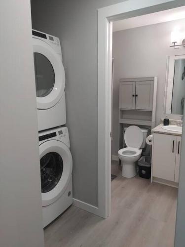 a bathroom with a washing machine and a toilet at Oasis of Happiness in Saskatoon