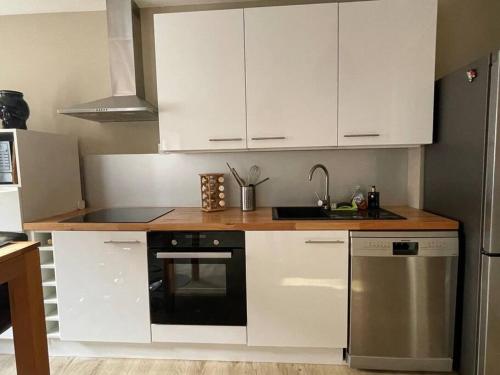 uma cozinha com armários brancos, um lavatório e um fogão em L'appartement charmant em Beynost