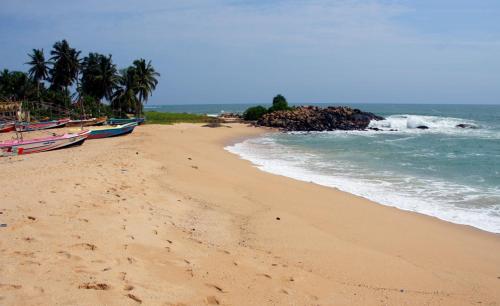 a beach with boats on the sand and the ocean at Villa Double T Residence in Ambalangoda