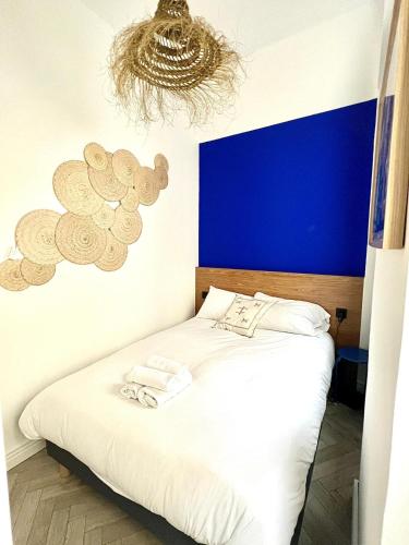 une chambre avec un lit blanc avec un mur bleu dans l'établissement Proche du Vieux-Port, avec balcon, à Marseille