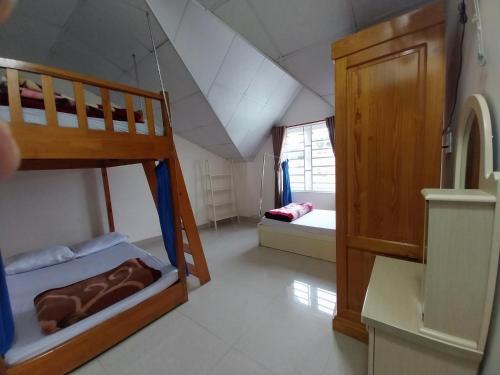 a bedroom with two bunk beds and a bathroom at Cam Ly Homestay in Da Lat