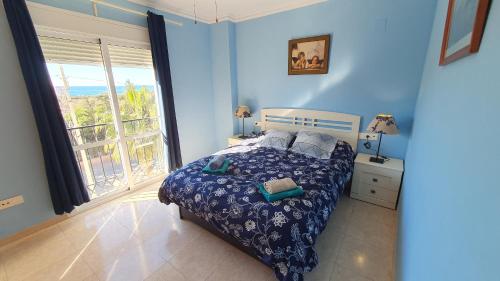 niebieska sypialnia z łóżkiem i dużym oknem w obiekcie Rico Apartaments Ricosol w mieście Torrox Costa