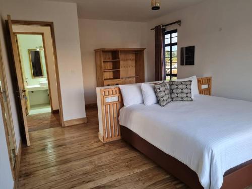 1 dormitorio con 1 cama grande y baño en The Landing Cottages, en Nanyuki