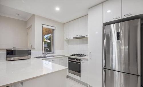a white kitchen with a stainless steel refrigerator at 2 Conveniently Quiet Cloverdale 2brpark in Perth